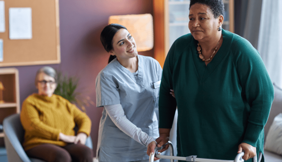 Nursing assistant helping an elderly lady to walk in a care home