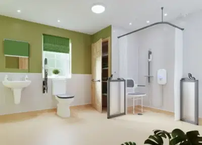 Wet Room Bathroom With Green Half Height Walls And Curtains, Toilet, Sink, And Large Walk In Shower With Seat And Grab Rails