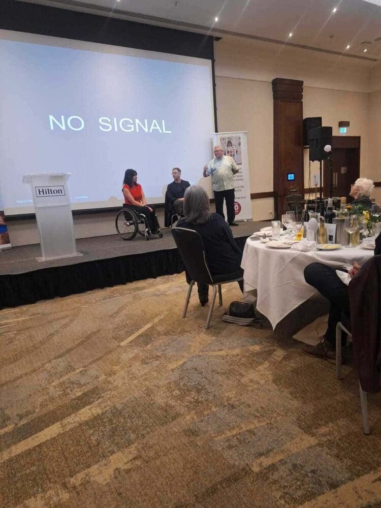 Event hosts on stage at the HCO Lunch presenting to the room