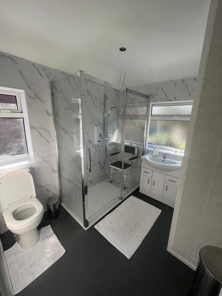 Mrs W's accessible bathroom, with marble wall panelling and low level mobility shower