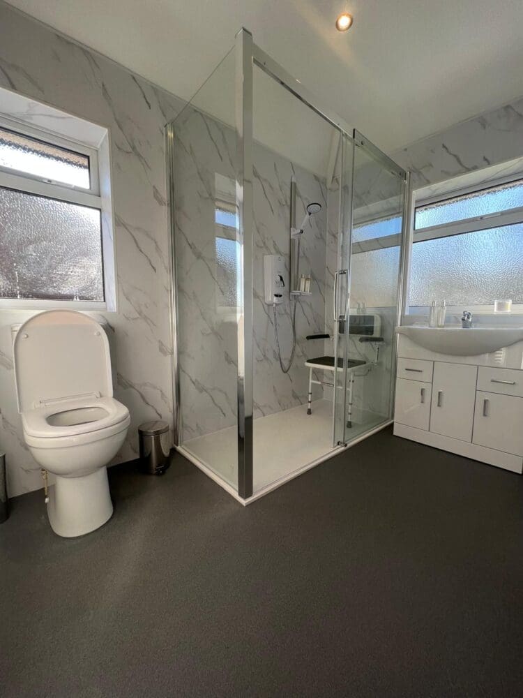 Mrs W's accessible bathroom, with marble wall panelling and low level mobility shower