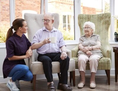 Carer Speaking To Two Elderly People